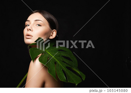 beautiful girl with palm leaves. Beautiful young woman with Make-up 103145080
