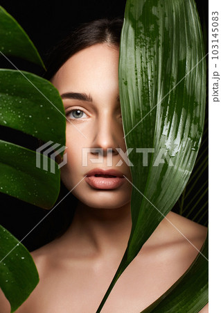 Beauty Portrait of brunette girl in palm leaves. Beautiful young woman with Make-up Beauty Portrait of brunette girl in palm leaves. Beautiful young woman with Make-up 103145083