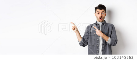 Excited man pointing left at logo and look with disbelief, saying wow at camera, checking out cool promo discount, standing on white background Excited man pointing left at logo and look with disbelief, saying wow at camera, checking out cool promo discount, standing on white background 103145362