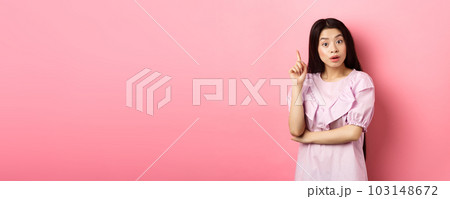Excited asian woman pitching an idea, raising finger in eureka sign, have plan or solution, standing on pink background Excited asian woman pitching an idea, raising finger in eureka sign, have plan or solution, standing on pink background 103148672