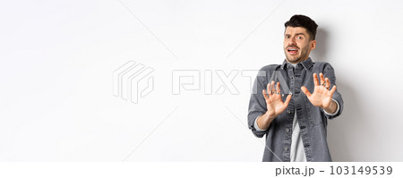 Stay away from me. Scared young man screaming and asking to stop, step back and look frightened, rejecting something bad, standing on white background 103149539
