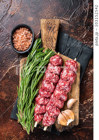 Raw traditional shish kebab Skewers with beef meat ans spices. Dark background. Top view 103152542