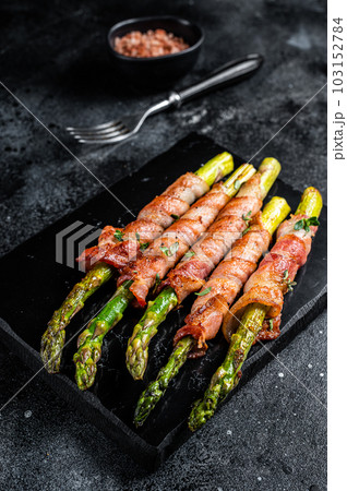 Asparagus Baked with bacon and spices. Black background. Top view 103152784