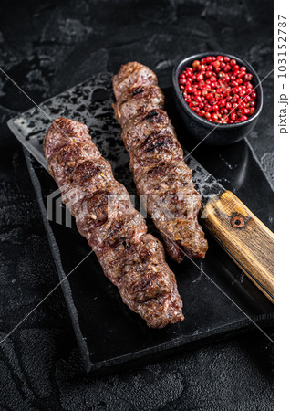 Urfa kebab, ground beef and lamb meat grilled on skewers. Black background. Top view Urfa kebab, ground beef and lamb meat grilled on skewers. Black background. Top view 103152787