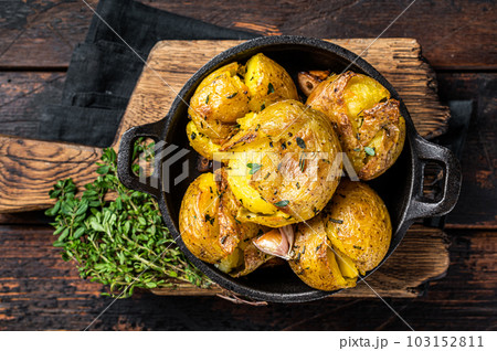 Crushed, Broken potatoes baked in oil with herbs. Wooden background. Top view Crushed, Broken potatoes baked in oil with herbs. Wooden background. Top view 103152811