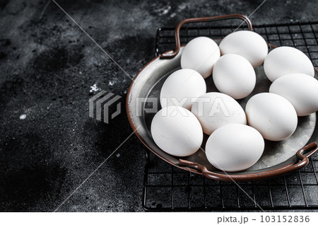 Plate with organic farm white chicken eggs. Black background. Top view. Copy space 103152836