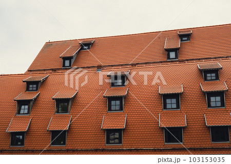 Corner with dormers Red Roofs of the city brown metal tiles roof of European house with windows. Typical European old brick roof with windows Corner with dormers Red Roofs of the city brown metal tiles roof of European house with windows. Typical European old brick roof with windows 103153035
