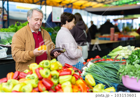 Aged man and woman customers buying pepper in open-air market Aged man and woman customers buying pepper in open-air market 103153601