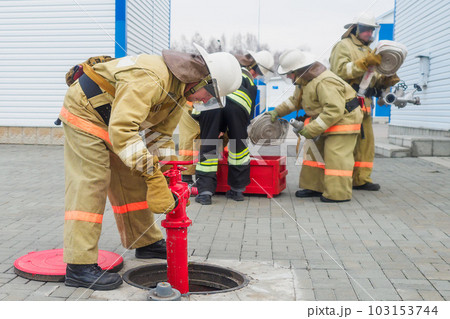 Fire brigade deploys equipment outside in open air and connects fire hydrant in well. Firefighting Fire brigade deploys equipment outside in open air and connects fire hydrant in well. Firefighting 103153744