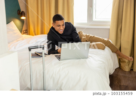 Smiling young man chatting online and feeling good Smiling young man chatting online and feeling good 103155459