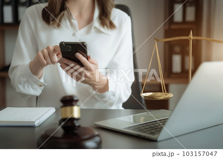 Justice and law concept.Female judge in a courtroom the gavel, working with digital tablet computer on wood table in sun light. 103157047