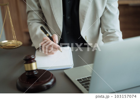 Justice and law concept.Female judge in a courtroom the gavel, working with digital tablet computer on wood table in sun light. 103157074