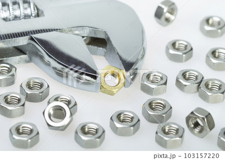 Metallic hex nuts and an adjustable wrench. Steel nuts and one brass Metallic hex nuts and an adjustable wrench. Steel nuts and one brass 103157220
