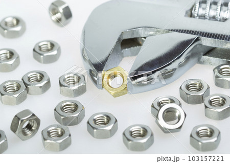 Metallic hex nuts and an adjustable wrench. Steel nuts and one brass Metallic hex nuts and an adjustable wrench. Steel nuts and one brass 103157221