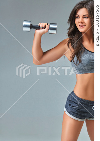 Nice sexy woman doing workout with dumbbells isolated over gray background Nice sexy woman doing workout with dumbbells isolated over gray background 103157505