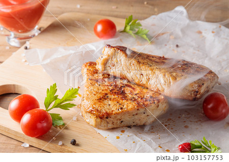 Slices of roast pork meat with tomato and ketchup on a wooden board. Slices of roast pork meat with tomato and ketchup on a wooden board. 103157753