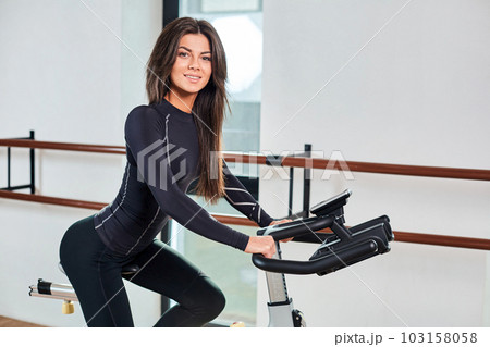 Muscular young woman working out on the exercise bike at the gym, intense cardio workout. Muscular young woman working out on the exercise bike at the gym, intense cardio workout. 103158058