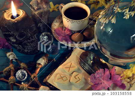 Magic crystal ball, skull candle and runes on altar ritual table. Occult, esoteric and divination still life. Mystic background with vintage objects 103158558