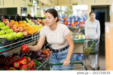Smiling woman in greengrocer s shop,picking bell pepper in small package Smiling woman in greengrocer s shop,picking bell pepper in small package 103158638