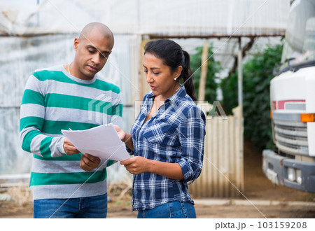 Man and woman farmers talking near car 103159208