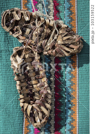 Vintage bast shoes on a green embroidered shirt. Ancient shoes. 103159522