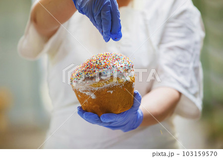 Hands decorate Easter bun. Professional baking Easter cakes. 103159570