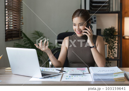 Smiling female entrepreneur sitting at home talking on her cellphone 103159641