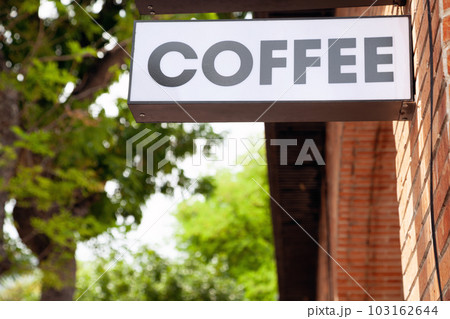 Black and white coffeehouse commercial sign with a word Coffee on a city street. Cafe advertisement lightbox hanging next to the entrance 103162644