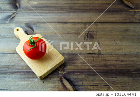 Tomato on a dark wooden table. 103164441