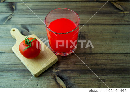 Tomato and tomato juice on a wooden table. Tomato and tomato juice on a wooden table. 103164442