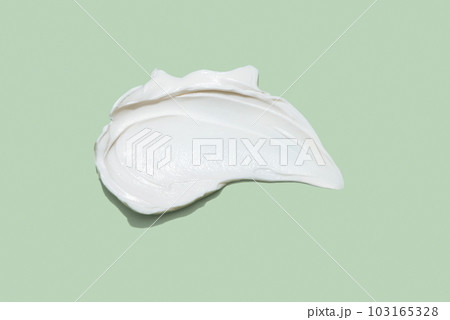 Liquid white cream smear isolated on green background. Beauty cosmetic smudge such as hair conditioner, creamy lotion, facial retinol serum, mask balm, cleanser, shower gel or shampoo top view 103165328