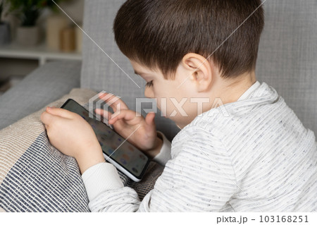 A preschool boy uses a smartphone, plays games on his phone. Screen Time, Parental Controls 103168251