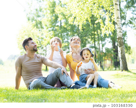 Happy family blowing bubbles in park 103168330
