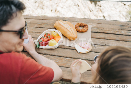 Close-up view of father and his school boy son on a family picnic in the mountains. Child kid and his dad taking a rest and enjoying a picnic while hiking in the mountains 103168489