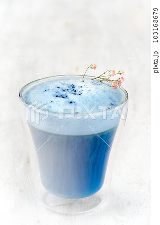 Blue matcha latte in a glass on a light white table. 103168679