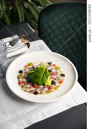 Seafood appetizer. Octopus Carpaccio on white plate. Mediterranean delicacy. Selective focus 103168698