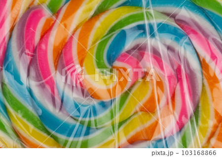extreme closeup of colorful lollipop candy in transparent plastic packaging on white background extreme closeup of colorful lollipop candy in transparent plastic packaging on white background 103168866