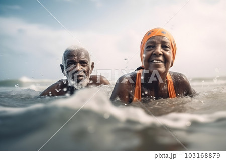 Mixed race senior couple swimming in ocean waves Mixed race senior couple swimming in ocean waves 103168879