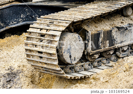 Muddy and sandy crawler excavator, dirty metal tracks with steel wheels close-up Muddy and sandy crawler excavator, dirty metal tracks with steel wheels close-up 103169524