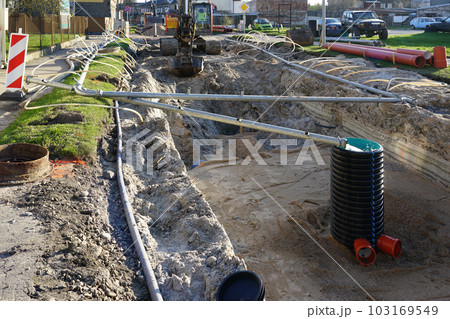 Street reconstruction view with dewatering system hoses and crawler excavators at deep trench Street reconstruction view with dewatering system hoses and crawler excavators at deep trench 103169549