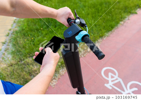 Hands of unrecognizable man using smart phone for modern electric scooter with app. Ecology and environment concept 103169745