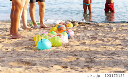on the beach, on the sand are balloons filled with water instead of air. people having a rest playing fun games on the beach 103173123