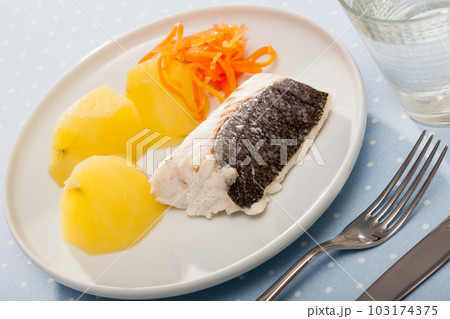 Pollock prepared on steam, served with boiled potatoes and carrots 103174375