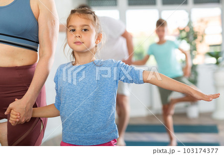 Little girl with family practicing yoga in studio Little girl with family practicing yoga in studio 103174377