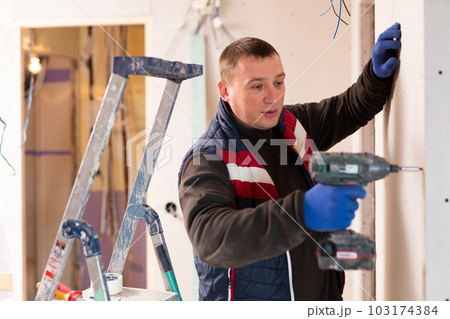 Repair man with drill working in apartment Repair man with drill working in apartment 103174384