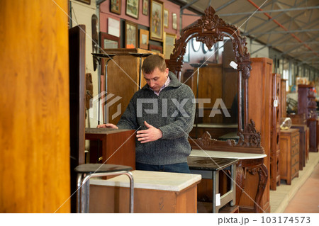 Man searching wooden furniture in store 103174573