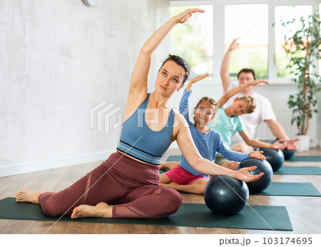 Family with two children doing yoga and pilates using soft ball in gym Family with two children doing yoga and pilates using soft ball in gym 103174695