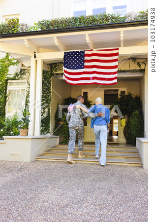 Happy caucasian woman and biracial male american soldier embracing outside the house 103174938