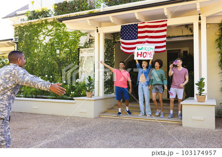 Happy diverse group of friends greeting biracial male american soldier outside the house Happy diverse group of friends greeting biracial male american soldier outside the house 103174957