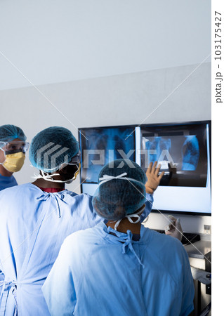 Diverse group of surgeons discussing x rays on screen in operating theatre, copy space Diverse group of surgeons discussing x rays on screen in operating theatre, copy space 103175427